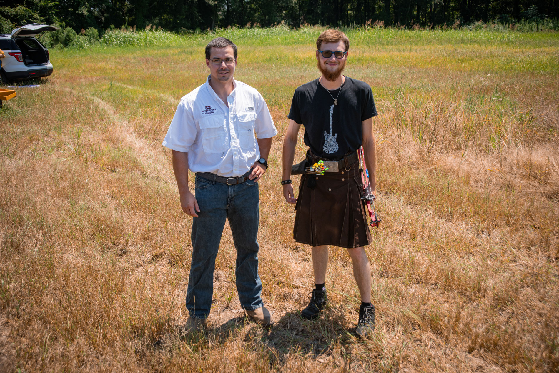 Two men standing in a field, smiling. 