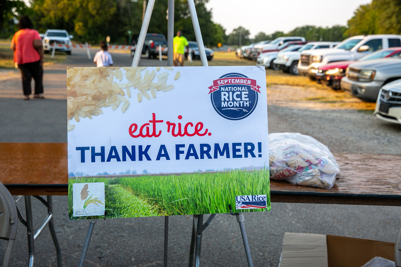 A sign that lists, “eat rice. THANK A FARMER!” on it with “ September National Rice Month” printed in the corner.
