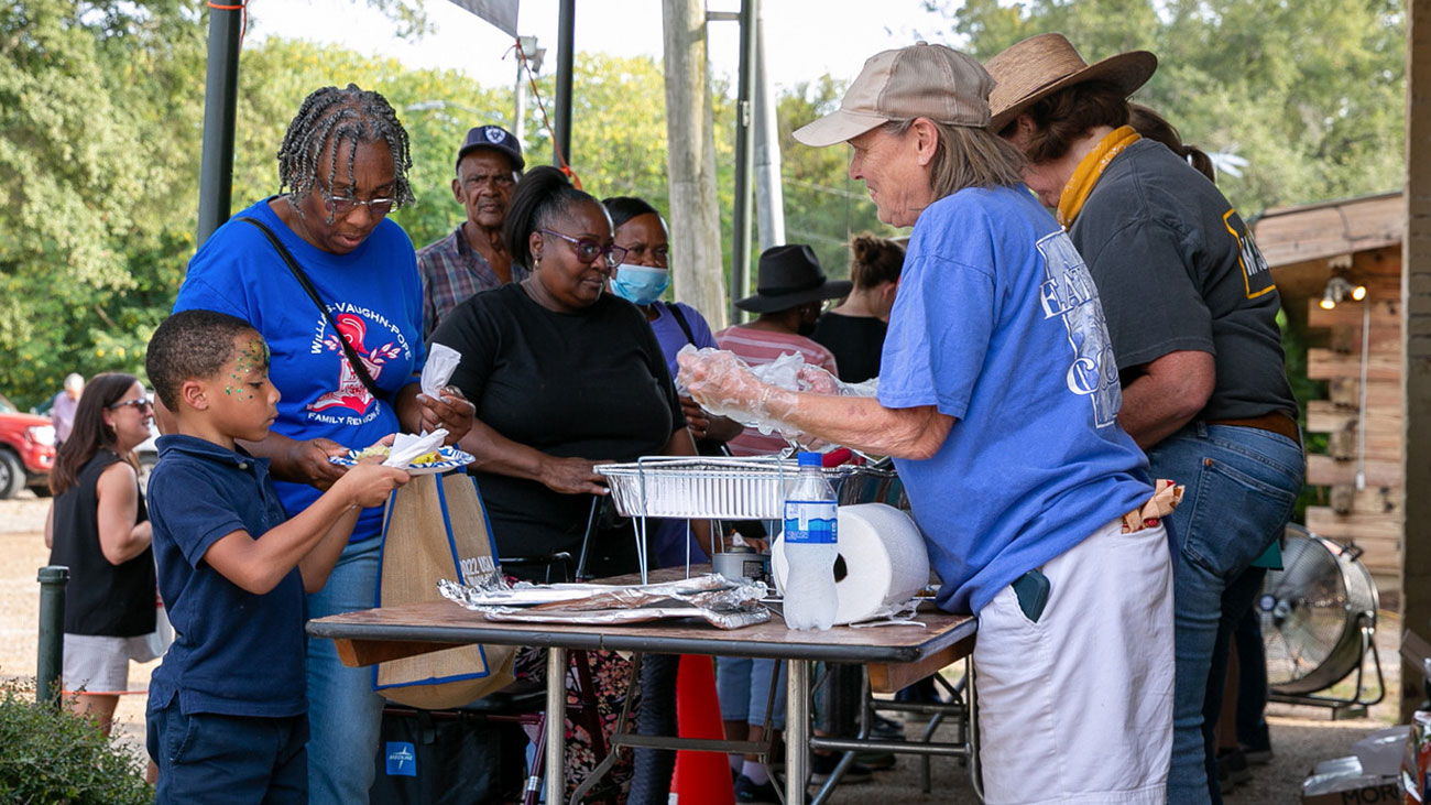 Women serving food to people in line.