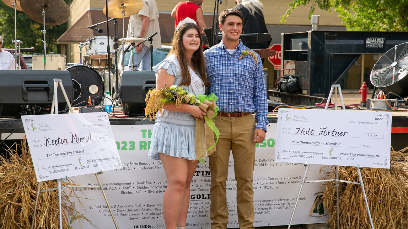 A woman wearing a tiara and holding a bouquet, standing beside a man wearing a polo.