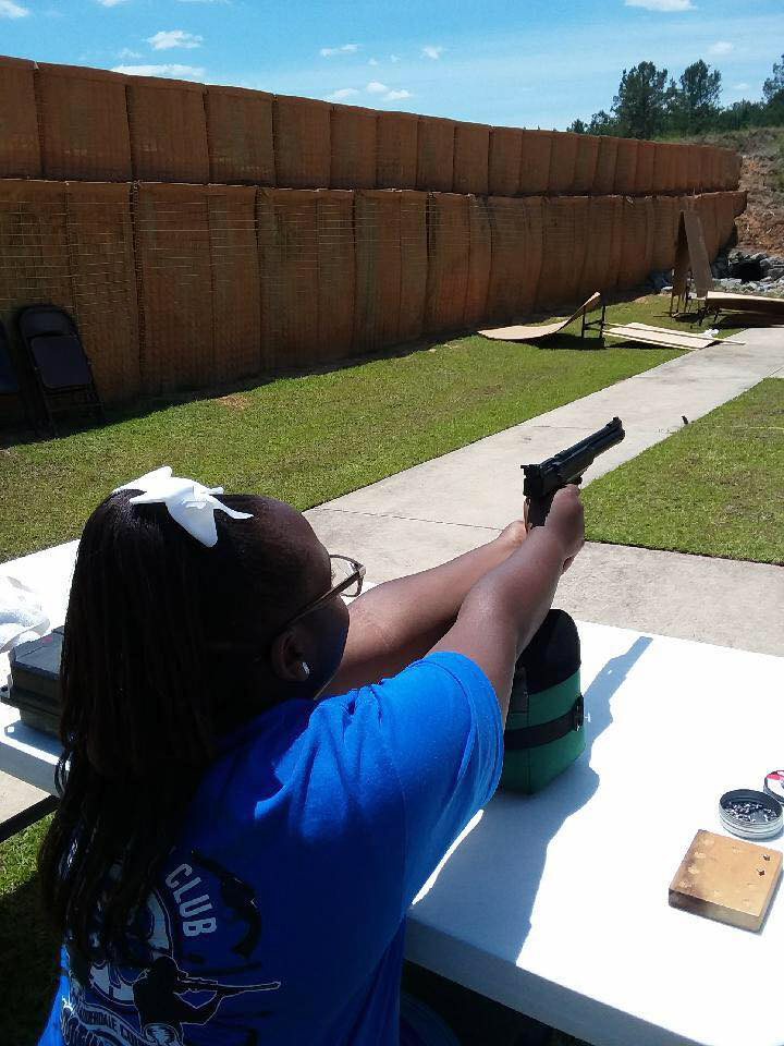 A girl aiming a pistol.