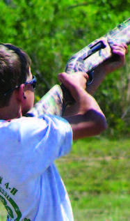 A Shooting Sport participant aiming a camo shotgun.